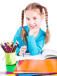 Cute llittle girl drawing in a sketchbook with colored pencils